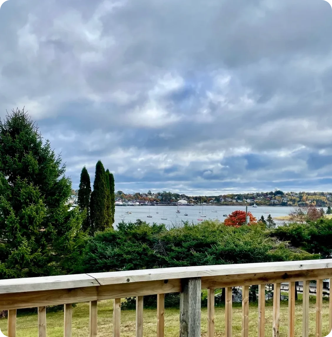 Lake view from wooden deck, cloudy sky.